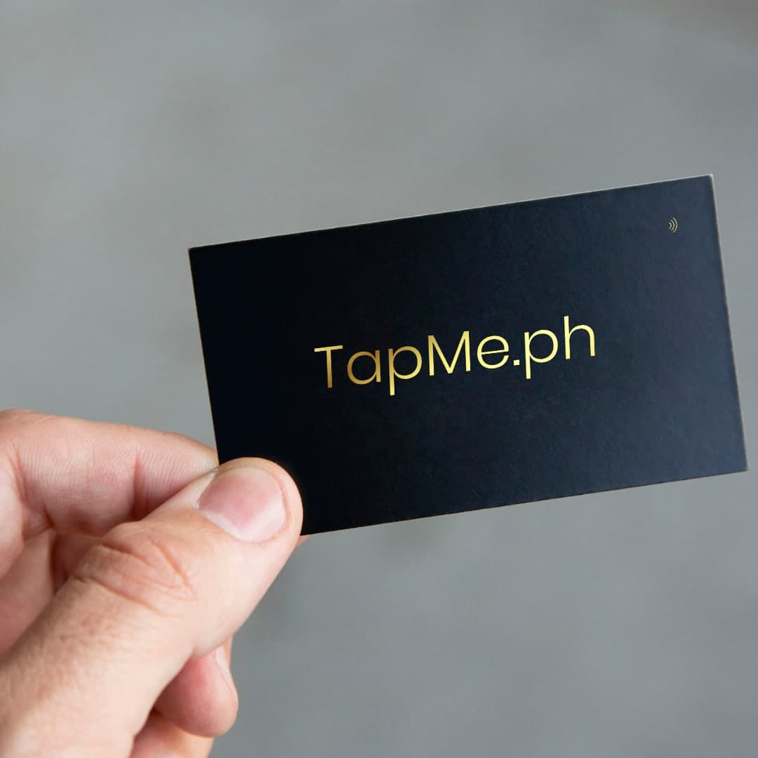 A hand holding the black and gold TapMe.ph card
